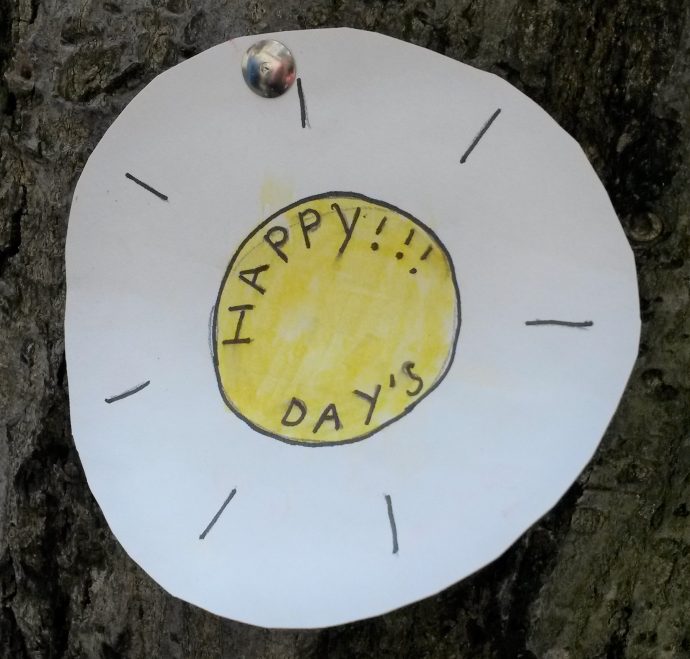 Sign on tree in shape of sun saying Happy days!!!