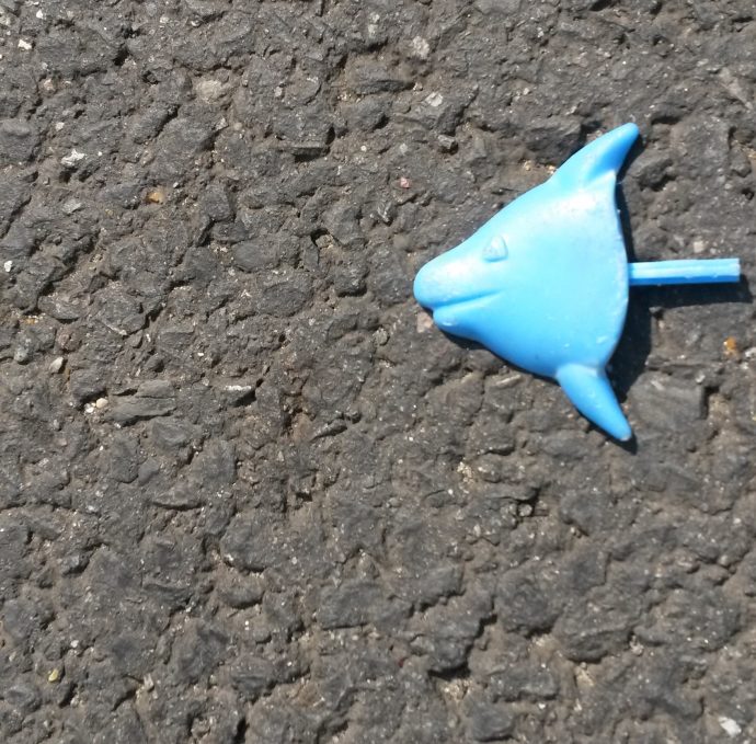 Blue plastic fish lying on the road