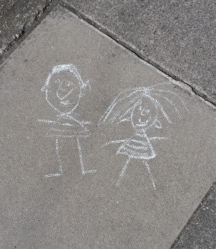 Children's chalk drawing on the footpath of a boy and a girl