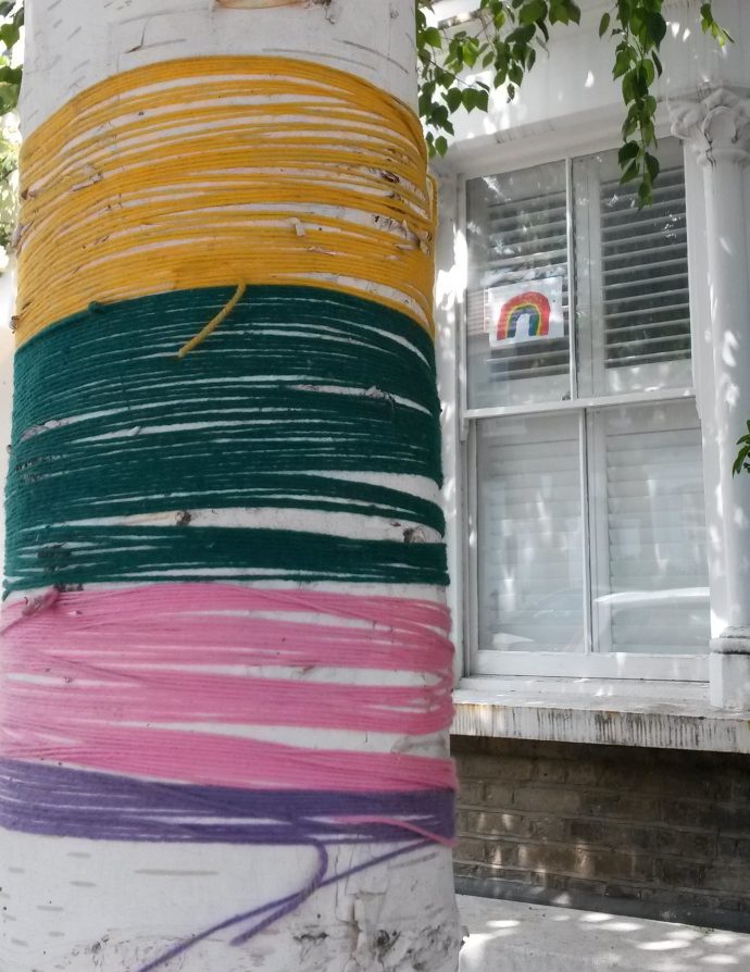 day 78 of lockdown - part of a tree wrapped with rainbow colours in yarn